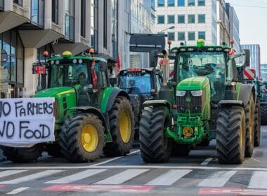 Article: Are conspiracy groups trying to hijack farmers’ protests? Image description: Tractors parked and road traffic at a standstill in the European Quarter in Brussels.