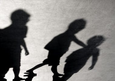 Headline: 'Neo-Nazi' group condemned for using children in by-election campaign Image description: Blurry shadows of three boys friends walking together