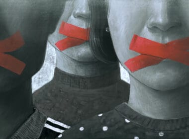 Article headline: Calls to tackle "abuse" lawsuits designed to block freedom of expression Image description: Artistic depiction of individuals with their mouths covered by red tape, conveying themes of oppression, restricted speech, or lack of freedom.
