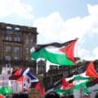 Article headline: Arms lobby group urged UK and Scottish Governments to crack down on Palestine Action Image description: Protesters wave Palestinian flags and hold placards during a pro-Palestine demonstration in Glasgow city centre, with historic buildings in the background.