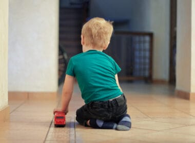 child with red toy facing away from the camera