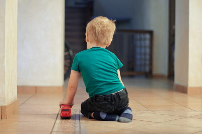 child with red toy facing away from the camera
